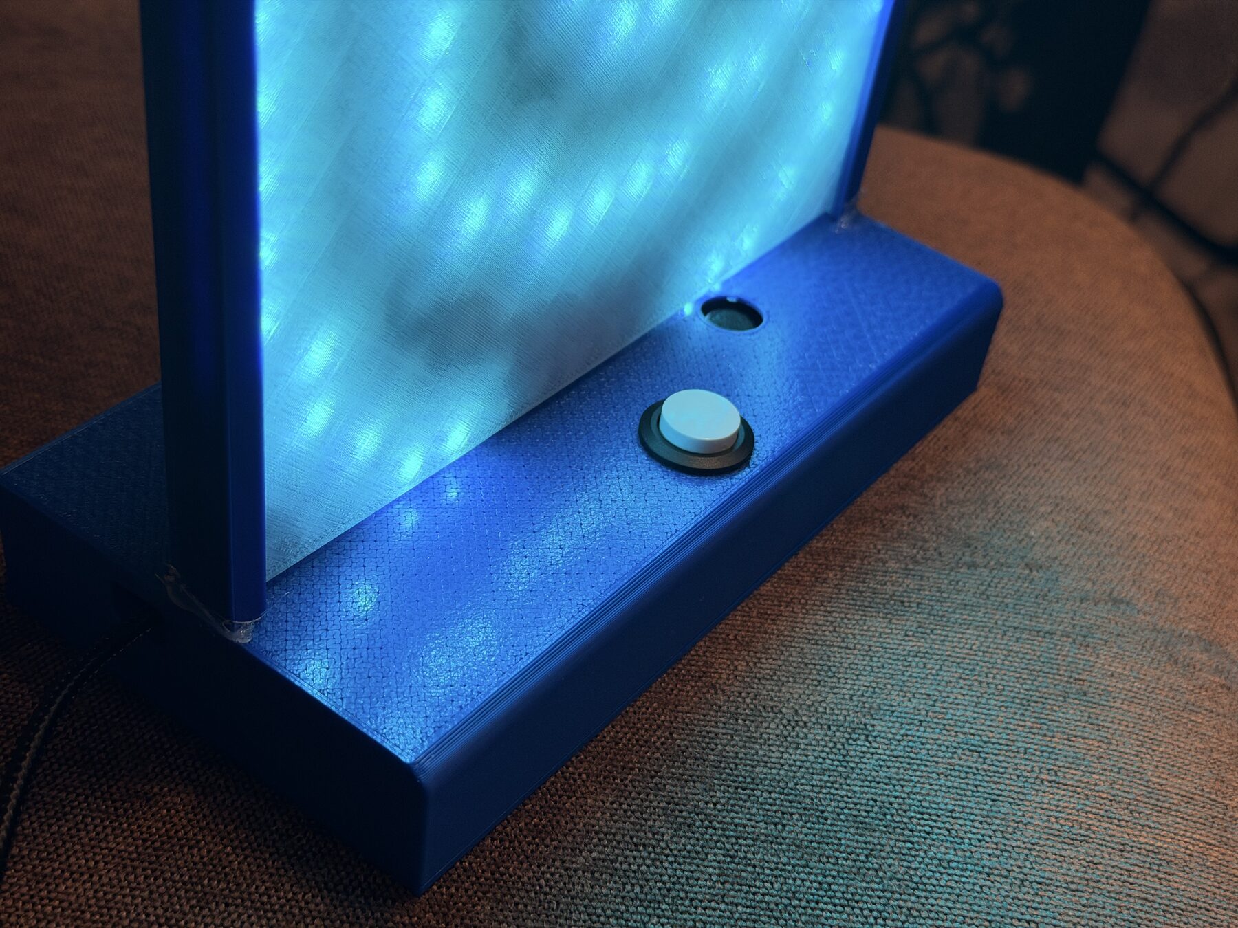 The lit base with blue light spilling onto the PLA around the button
